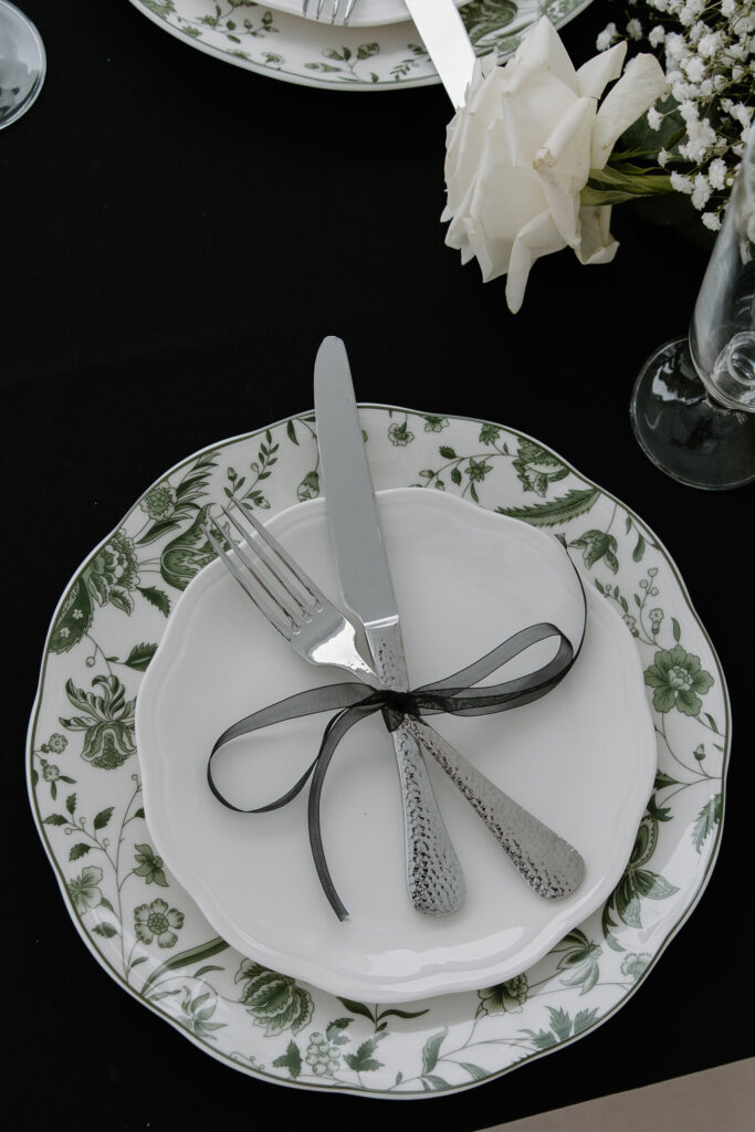 Wedding table arrangement with emerald floral plate design and ribbons